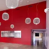 Le foyer de la salle des Utins : un grand mur rouge, des suspensions blanches en fil.